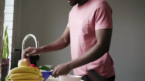 Man washes lettuce leaves in kitchen