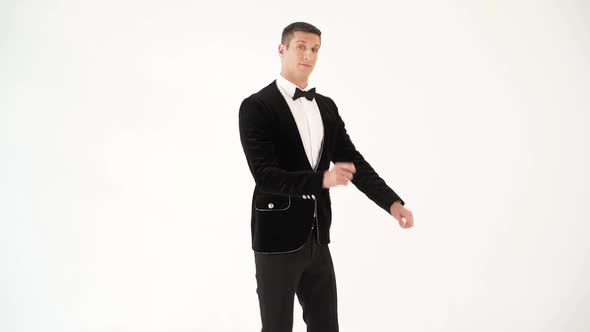fun man in a black suit with a bow tie is showing dance of dancer on the white background
