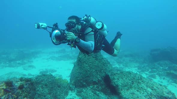 A slow-motion video of an underwater cameraman taking photos in the ocean of marine life with underw