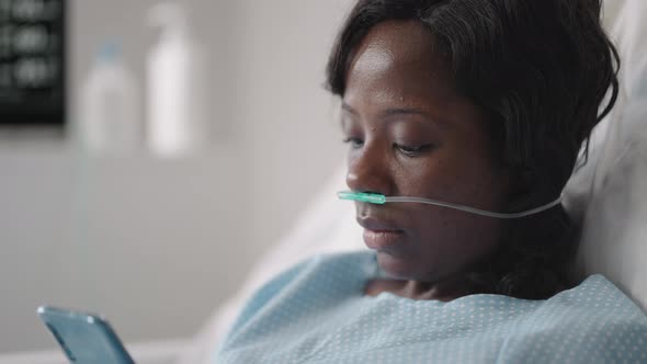 A Young Woman Writes a Message on Her Phone While Lying in a Hospital Ward alt