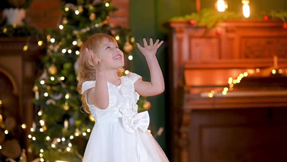 child catches falling white feathers like snow flakes.