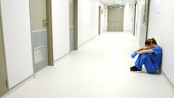 Tensed female doctor sitting in corridor