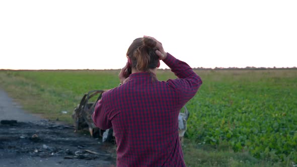 A Young and Stylish Boy Calls the Police Near the Burned Car on the Road. A Man in a State of Shock