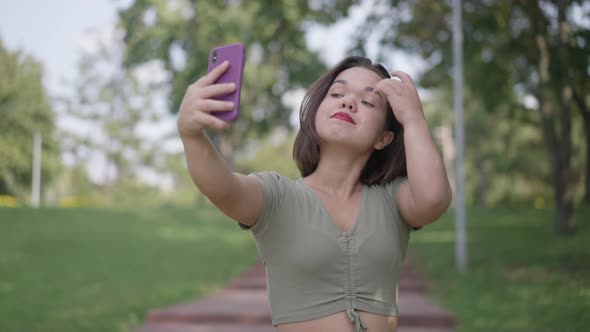 Beautiful Little Woman with Dwarfism Taking Selfie on Smartphone in Slow Motion Outdoors