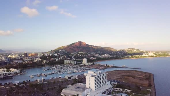 Drone rising to reveal Townsville city and Castle Hill on a sunny morning.