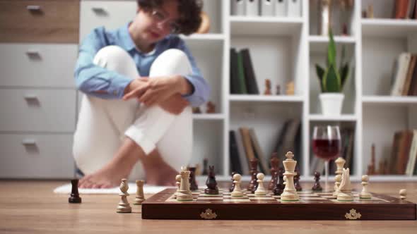 A Girl A Chess Player Sits On The Floor In Front Of A Chessboard Having A Pensive Look On Her Face