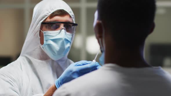 Caucasian male medical worker wearing protective clothing taking dna swab sample from patient in lab