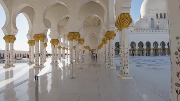 Slow motion walk through the white and golden hallway of the Grand Mosque in Abu Dhabi