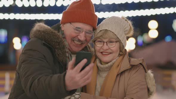 Elderly Couple Taking Selfie On Ice Rink
