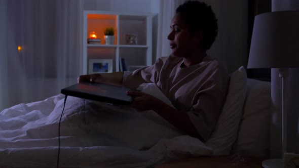 Woman with Laptop in Bed at Home at Night