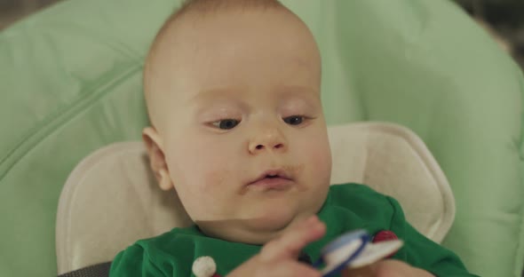 Close View of Oiled with Puree Toddler Relaxes in Kid Chair and Sucks Pacifier