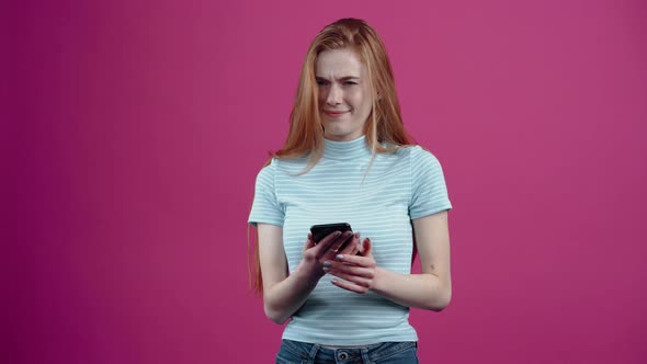 Angry Young Woman with the Phone in Her Hand Shows Her Thumb Down in Disapproval in a Blue Casual