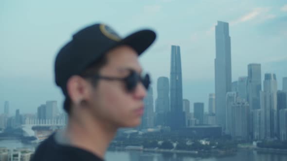 Medium shot of young asian photographer capturing urban downtown from rooftop in the early morning