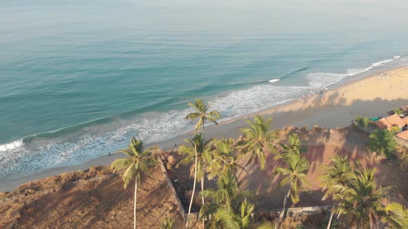 Tropical beach shoreline with warm Arabian sea waters and palm trees in Varkala, Kerala, India