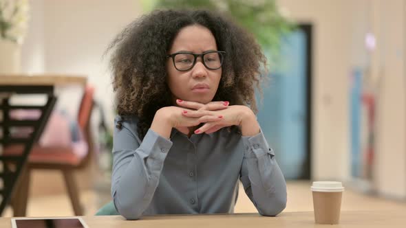 Young African Woman Sitting in Office and Thinking