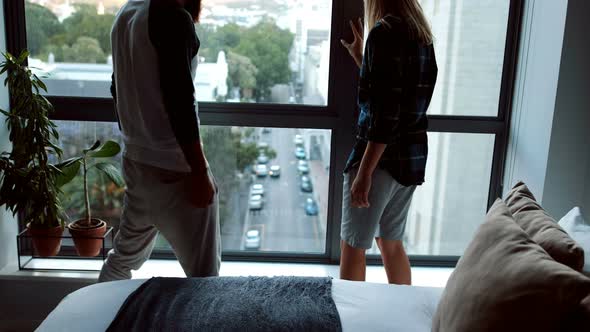 Couple looking through window in bedroom 