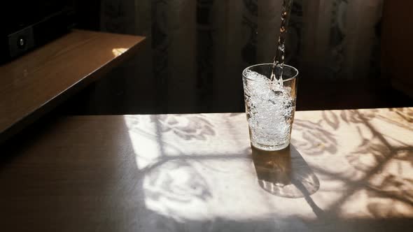 A Jet of Water in Slow Motion Falls Into a Glass Creating Air Bubbles After Falling Splashing Drops