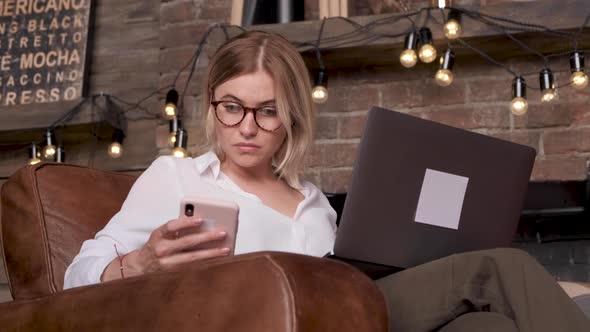 A Young Woman Uses A Smartphone And Laptop Communicates With Colleagues Via Messenger