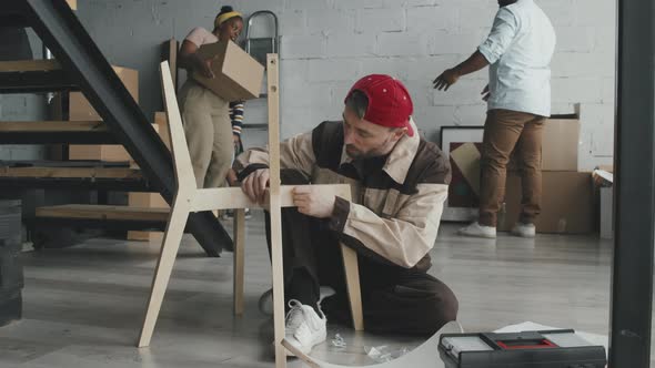 Family Moving into House and Handyman Assembling Chair