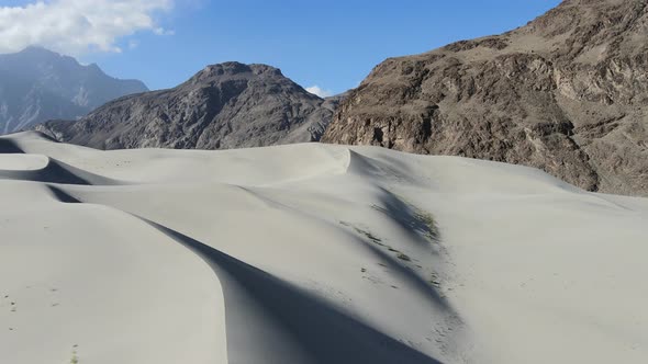 aerial drone flying backwards revealing large sand dunes in the Cold Desert of Skardu Pakistan overl