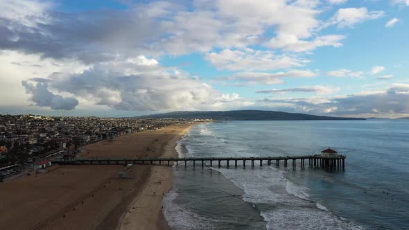 View of a pier with a house on the coast in front of a mountain overlooking the sea, zoom. Drone sun