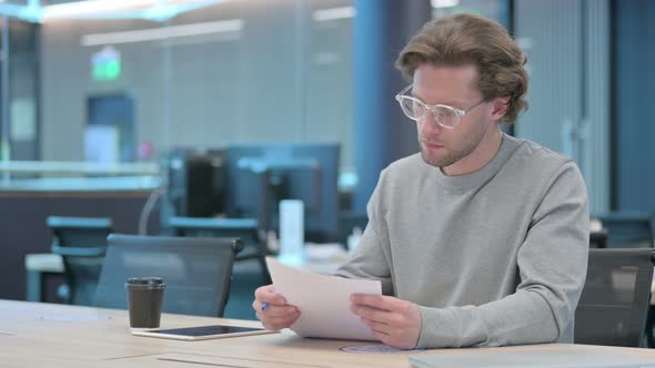 Young Businessman Reading Documents in Office