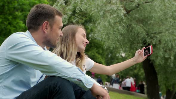 Young Couple Taking Self Portrait By a Lake. Man and Woman on Vacation in Taking Selfie with Their