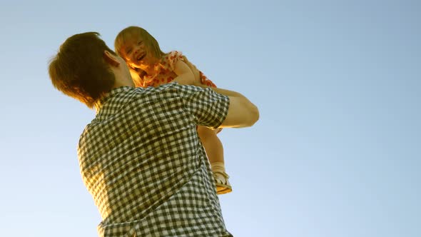 Dad Threw Baby Into Blue Sky. Concept of a Happy Childhood. Dad Throws Baby Up High Against Sky. Dad
