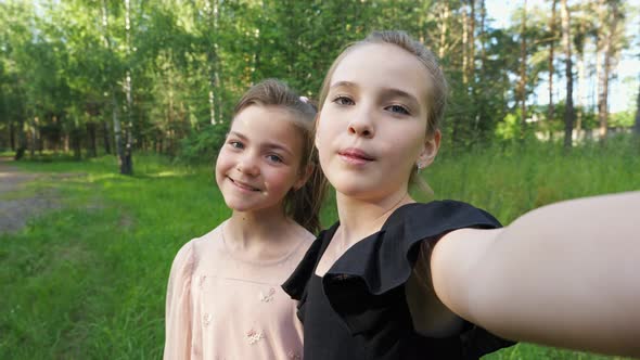 Couple of Girls Makes Selfie Grimacing in Park Closeup