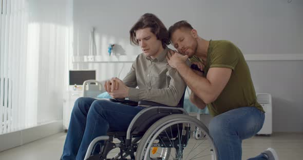 Young Man Hugging and Supporting Depressed Boyfriend in Wheelchair