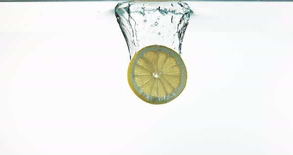 Yellow Lemons, citrus limonum, Fruits falling into Water against White Background, Slow Motion 4K