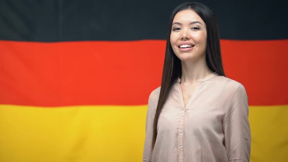 Beautiful Asian Female Showing Thumbs-Up Sign Against German Flag Background