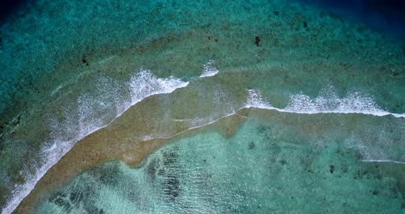 Daytime fly over clean view of a white sand paradise beach and aqua turquoise water background in co