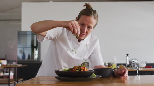 Caucasian female chef preparing a dish and smiling in a kitchen