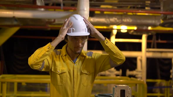 Young Man in a Yellow Work Uniform, Glasses and Helmet in Industrial Environment,oil Platform or