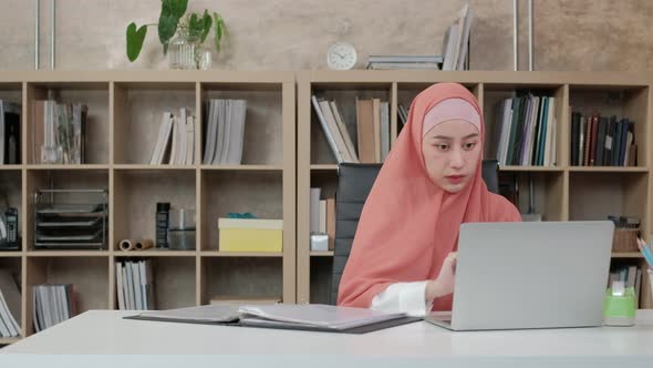 A beautiful Islamic businesswoman works in an office.