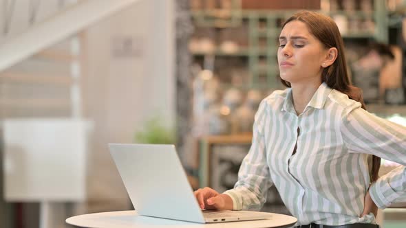 Young Latin Woman with Laptop Having Wrist Pain in Cafe 