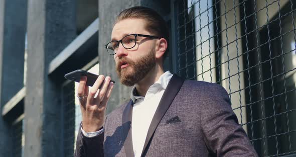 Businessman in Glasses Agrees on Meeting with His Business Partner on Phone while Standing Outdoors