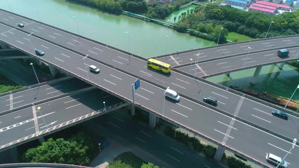 Aerial Tilt View of a Highway Overpass Multilevel Junction with Fast Moving Cars Surrounded By Green