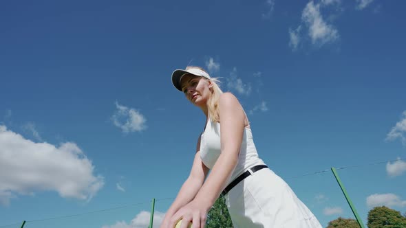 Young Woman Tennis Player Hits a Ball Off the Floor in a Outdoor Court Low Angle View Training Day