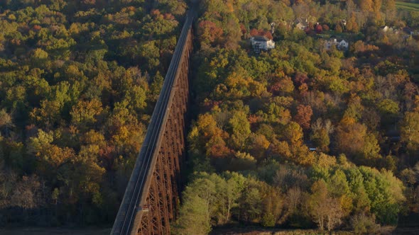 Aerial of railroad bridge between valley covered with autumn forest