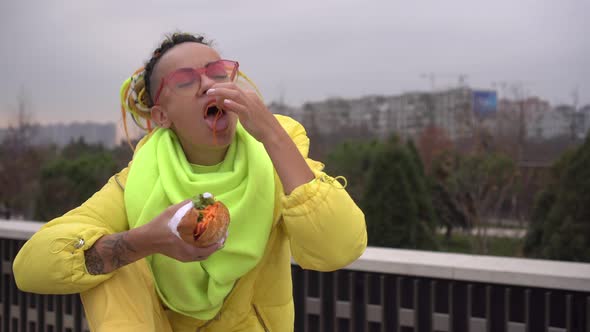 Modern Woman Eating a Sandwich Outdoors