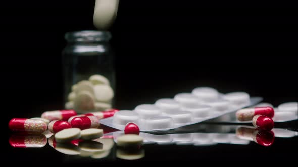 Closeup of Falling Medicine Tablets on Black Background Shooting of Red and White Drugs on the Table