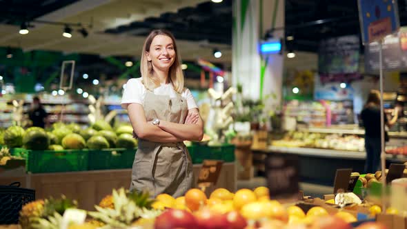 portrait of saleswoman, woman smiling and looking at camera in supermarket. 