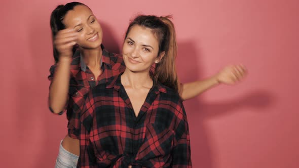 Two young beautiful smiling hipster girls in summer clothes posing in studio