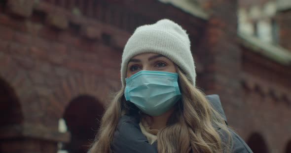 Close Up Portrait of a Beautiful Young Woman Wearing Protective Medical Face Mask and Standing on