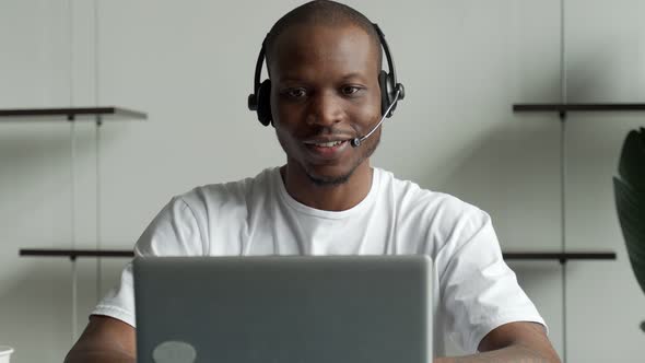 A Black Man is a Customer Service Operator with a Handsfree Headset Working in an Office