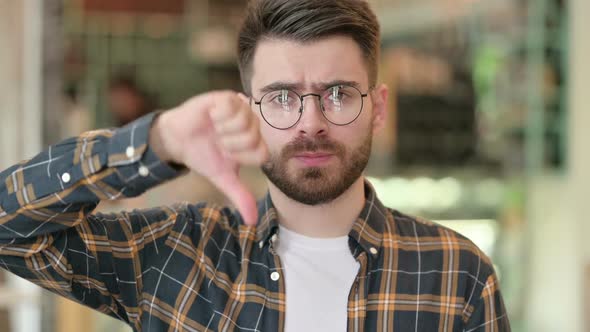 Portrait of Disappointed Young Man Doing Thumbs Down