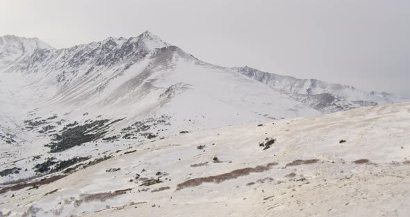 Aerial helicopter shot fly through snowy river valley, following along river, ice and snow surround 