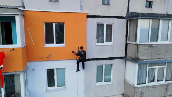 Painting and Decorating Buildings. Worker on a Construction Site of a High-rise Building. Dangerous